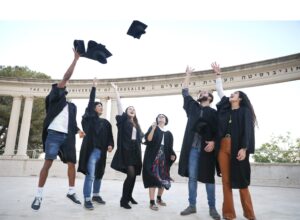 groupe d'étudiants gradués joyeux lançant leur couvre-chef en l'air